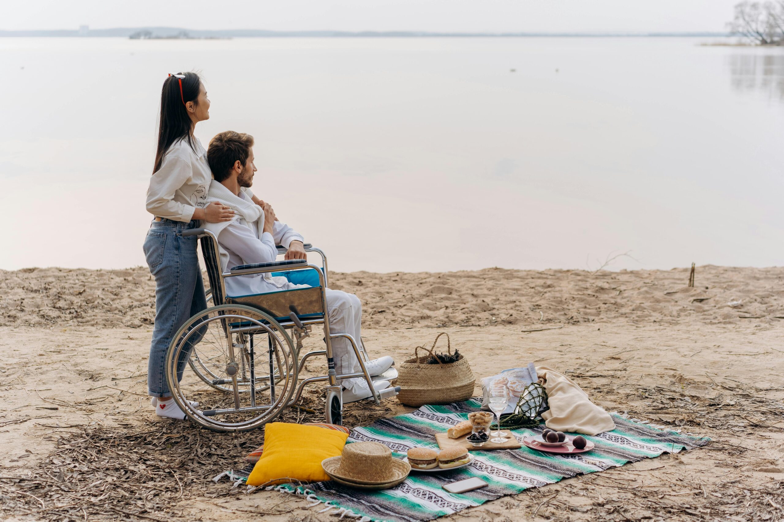 Couple enjoying a romantic picnic by the seaside, emphasizing inclusivity and relaxation.