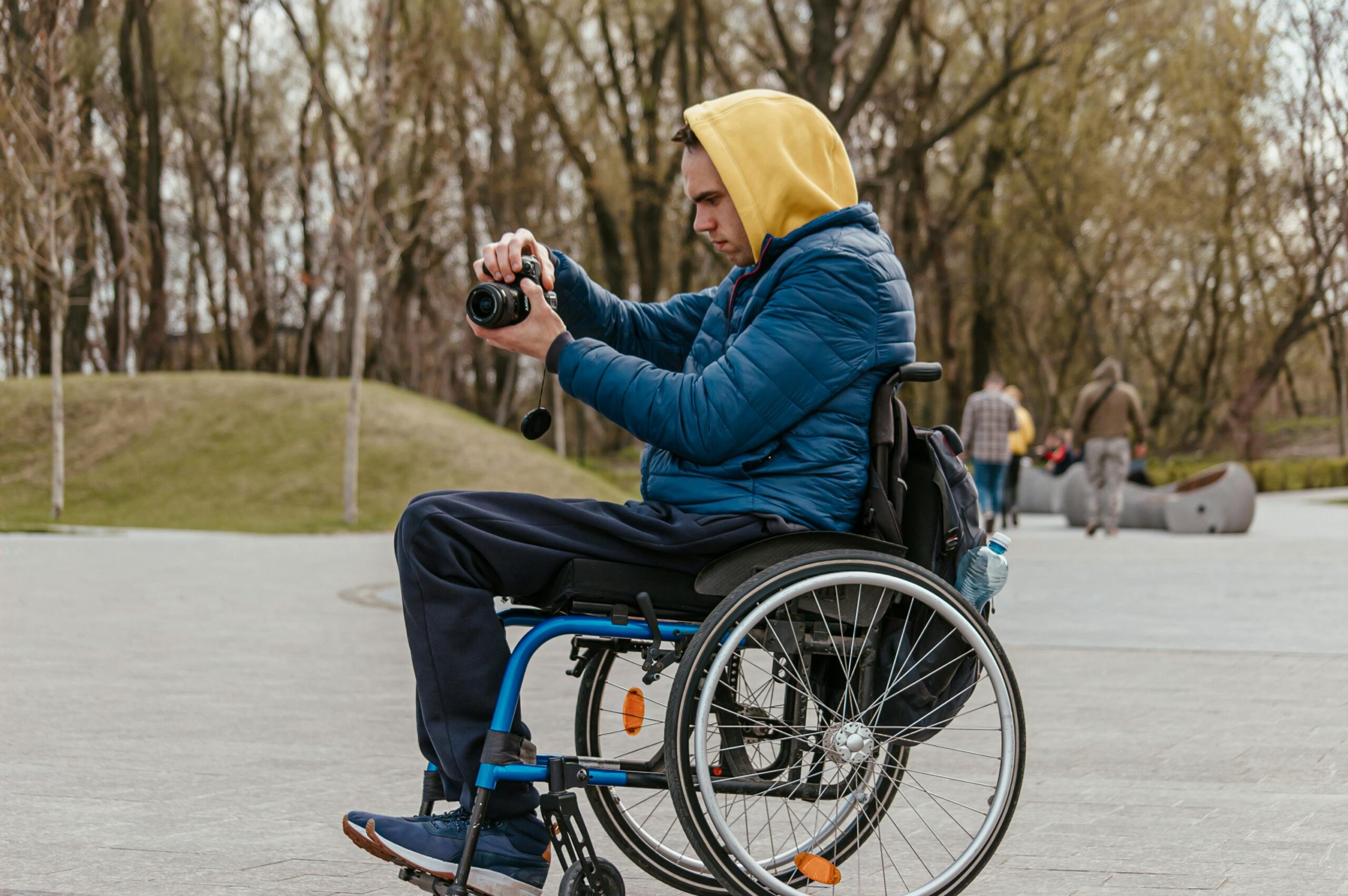 Man in a wheelchair capturing photos with a camera in an outdoor setting, Dnipro, Ukraine.